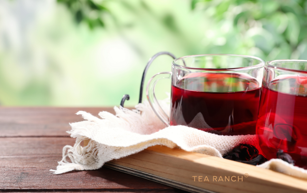 Ruby-Red Hibiscus Herbal Tea Bright ruby-red hibiscus herbal tea served in a clear glass cup with dried hibiscus flowers